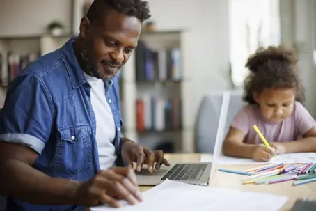father reviewing documents while his child colors